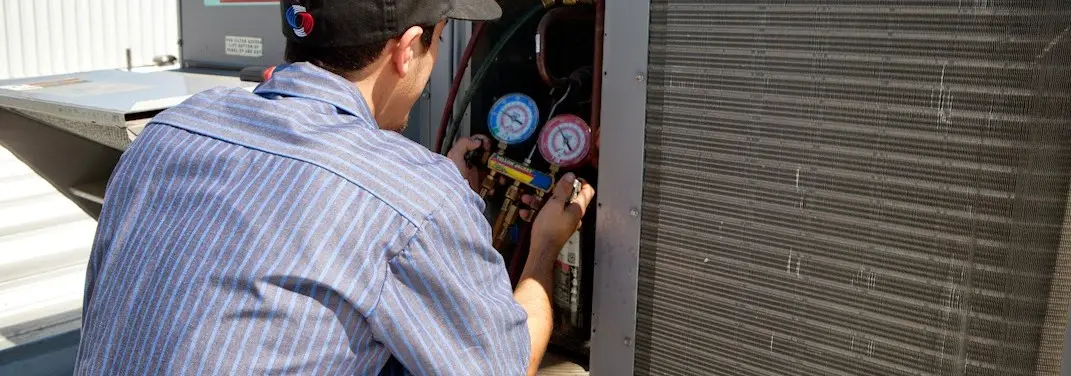 HVAC technician servicing a condenser unit in Airway Heights